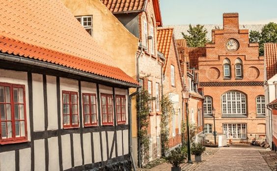 En hyggelig brostensgade i Viborg med et bindingsværkshus badet i aftensol
